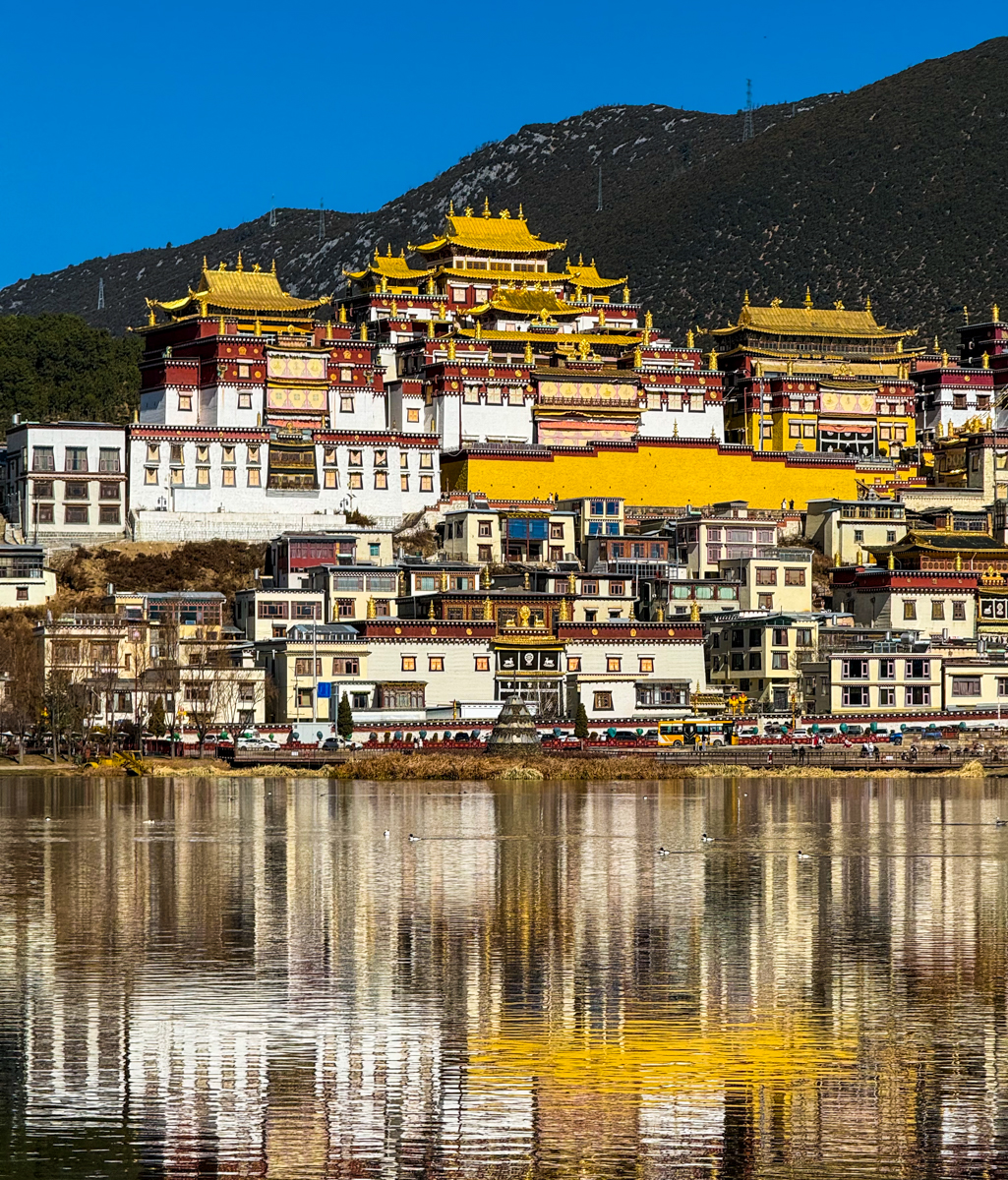 香格里拉松赞林寺与拉姆央措湖全景，小布达拉宫金顶在高原阳光下闪耀